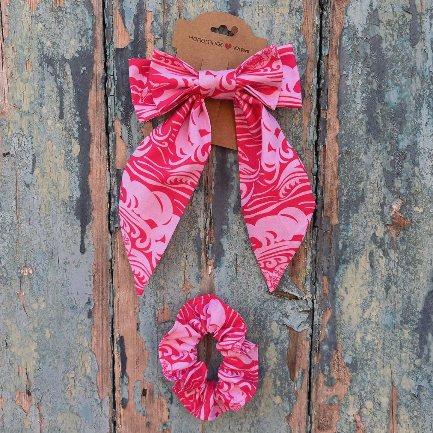 Pink hair bow and scrunchie set on a textured wooden background